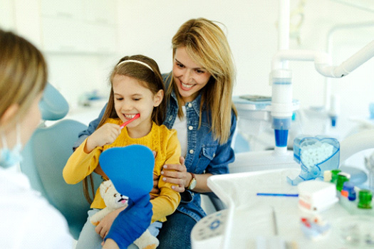Child sitting on mom's lap while brushing teeth