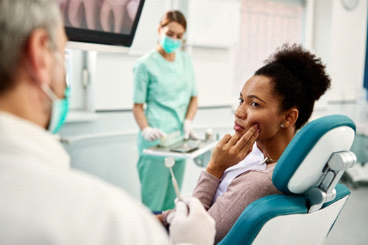 Patient with toothache looking at dentist in treatment chair