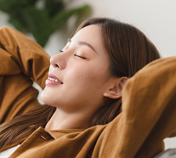 Woman relaxing on a couch with her hands behind her head