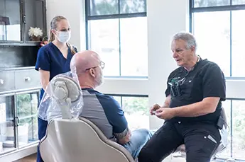 Woman in the dental chair looking at her smile in a mirror