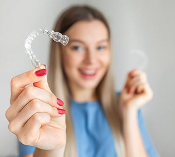 Woman with red nails in blue shirt holding SureSmile to camera