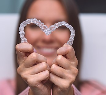 Woman holding SureSmile trays in the shape of a heart