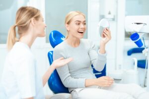 Cosmetic dentistry patient admiring her smile in mirror 
