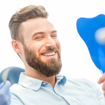 man looking at his smile in the mirror